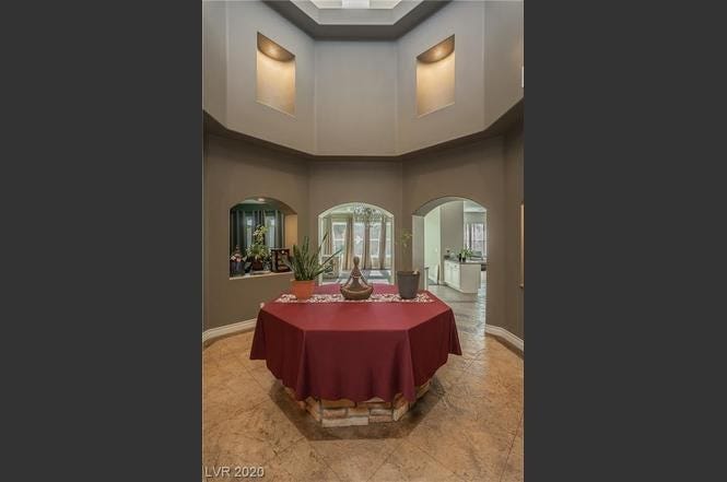 An octagonal gray room with a hexagonal table in the middle covered with a red tablecloth.