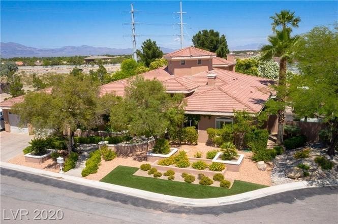 External, elevated shot of a large house with an orange roof with bright blue skies and mountains in the background.
