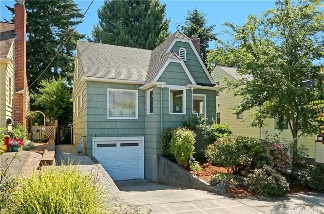 A small green Craftsman house with a short, sloping driveway.