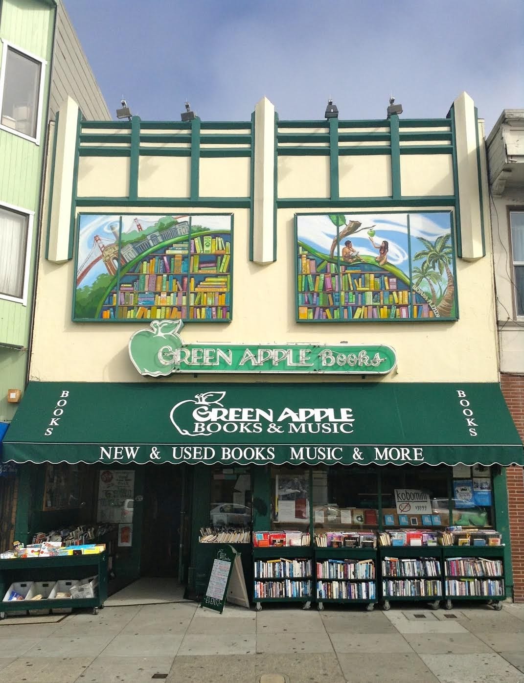 Green Apple Books and Music shop—a store with a green awning, a green neon sign, and cases of books on the sidewalk.