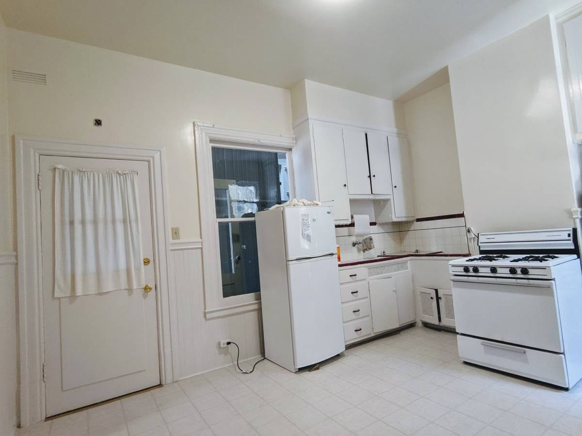 A small kitchen without anyplace else to put the refrigerator than in front of the window, blocking half of it.