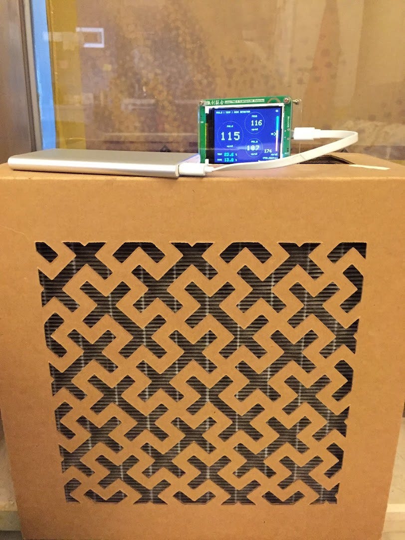 An air quality monitor on top of an air purifier showing a reading of 116 vs 115.