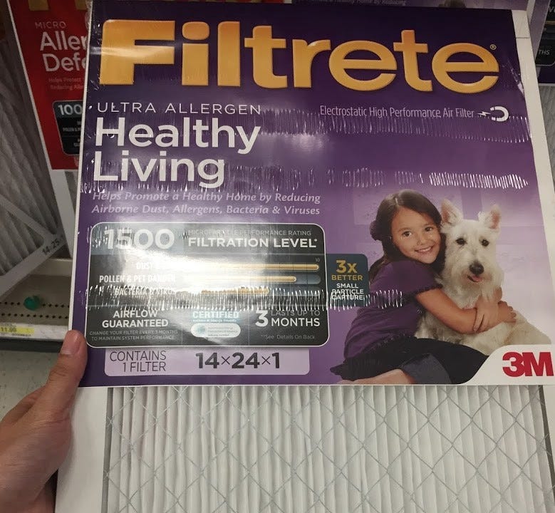 A hand holding a Filtrete filter in a store.