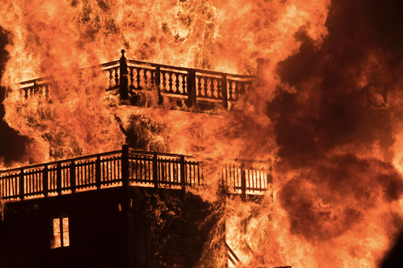A multi-level outdoor deck engulfed in flames.