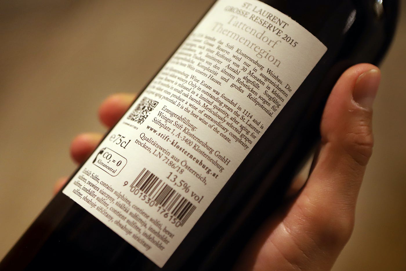 A hand holding up a bottle of Austrian winery Stift Klosterneuburg’s St. Laurent 2015 Grosse Reserve red wine.