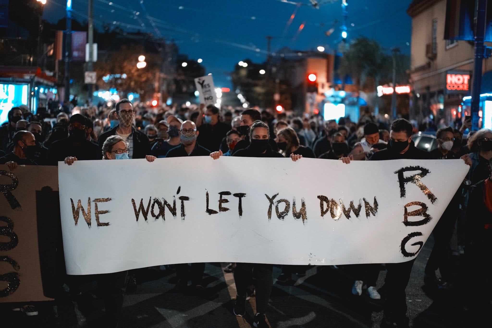 A crowd holding a white banner that reads, “We won’t let you down, RBG.”