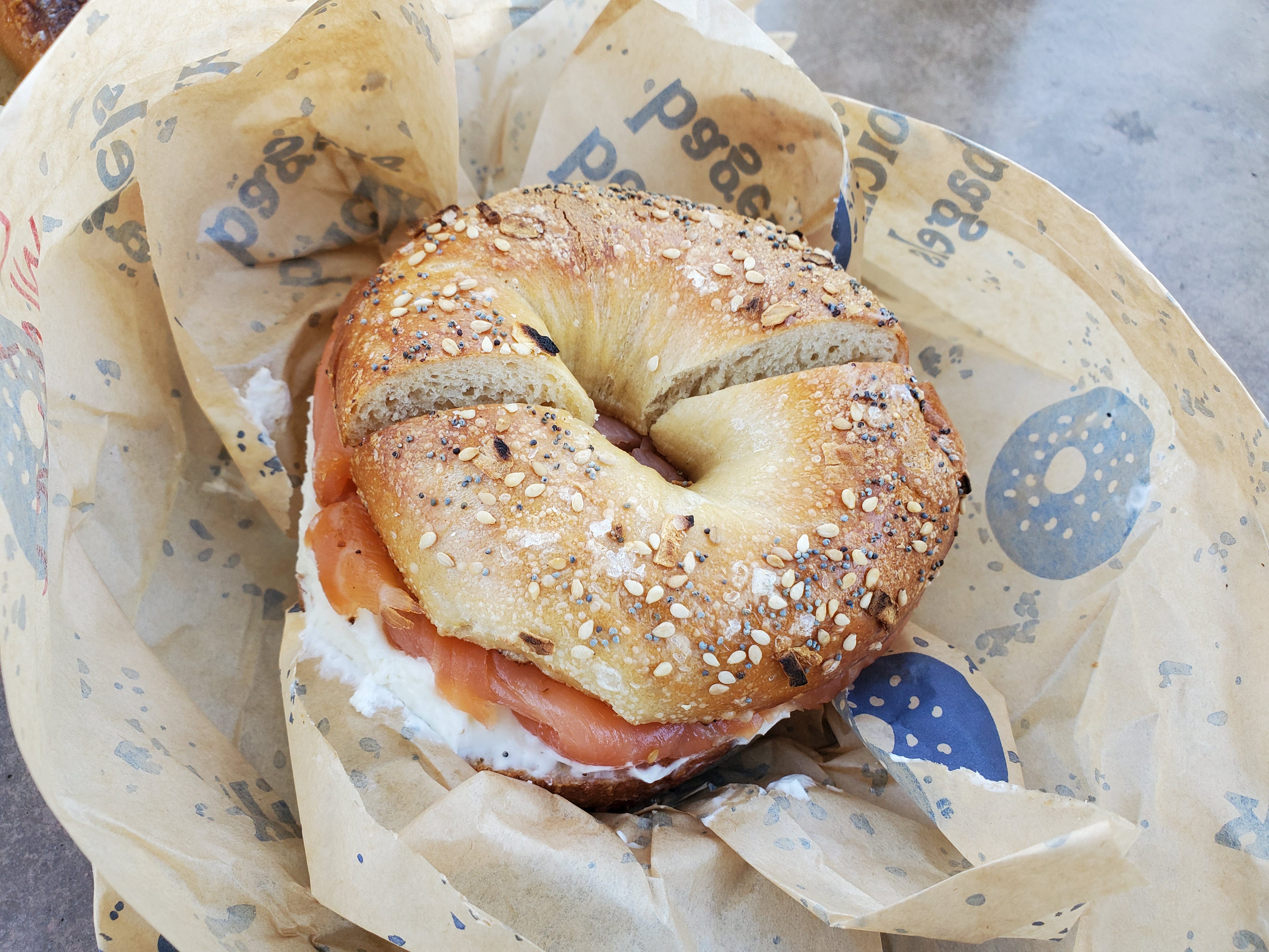 A lox bagel from Boichik, sitting on a paper wrapper with bagels on it.