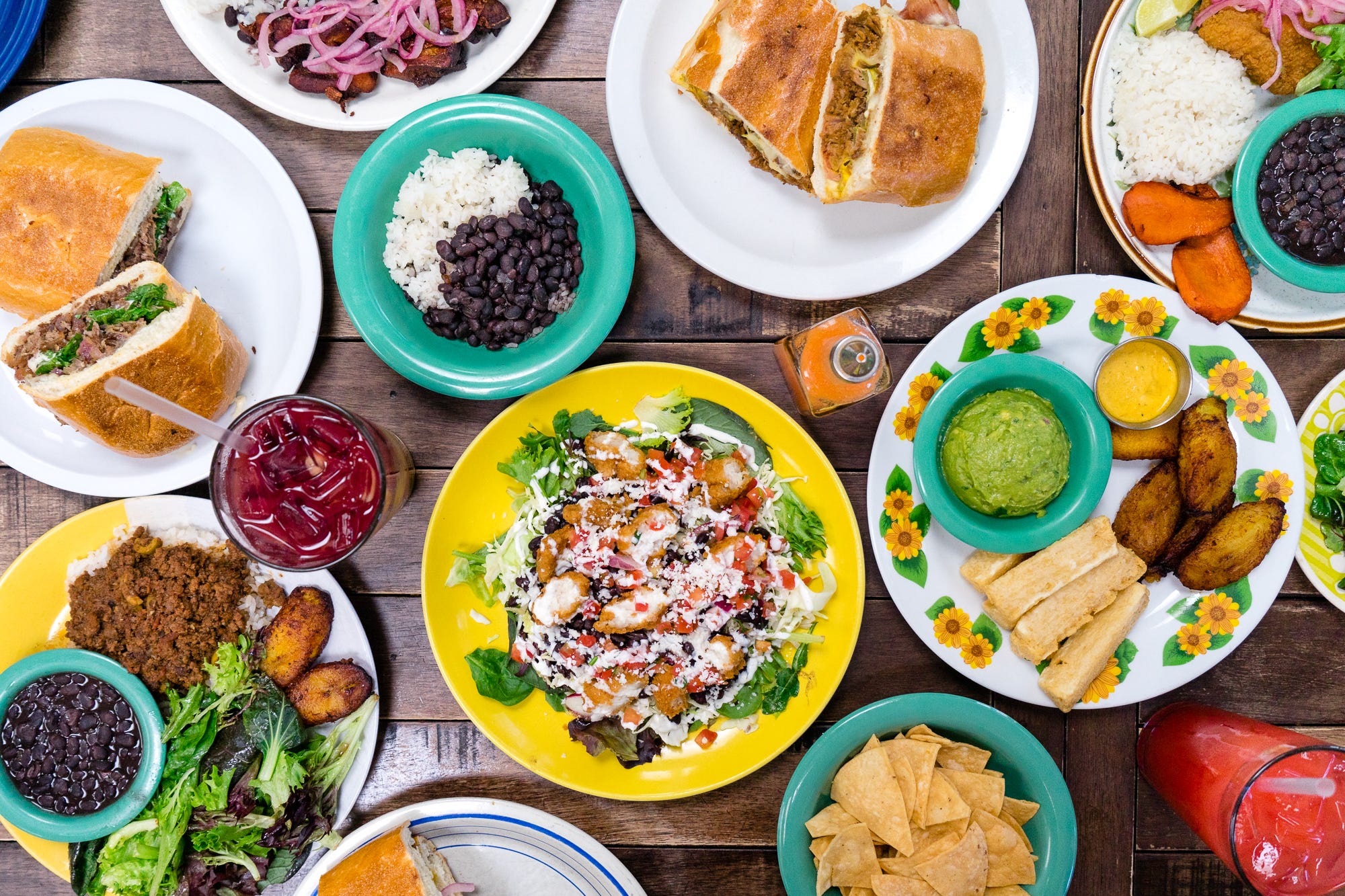 A wooden tabletop covered with colorful dishes filled with food.