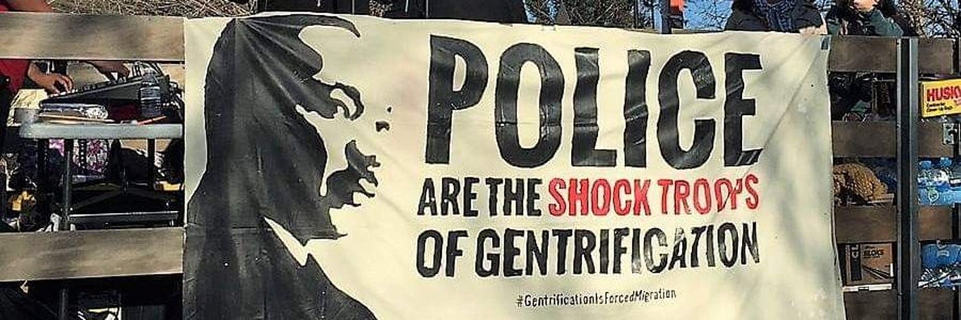 A banner at a protest: MLK Jr.’s face + “Police are the shock troops of gentrification.”