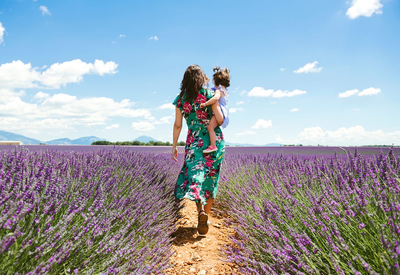 Mother and daughter walking among lavender fields in the summer.