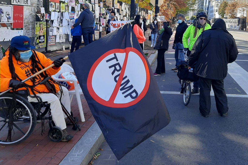 Protestors outside the White House, one of them holding an anti-Trump flag.