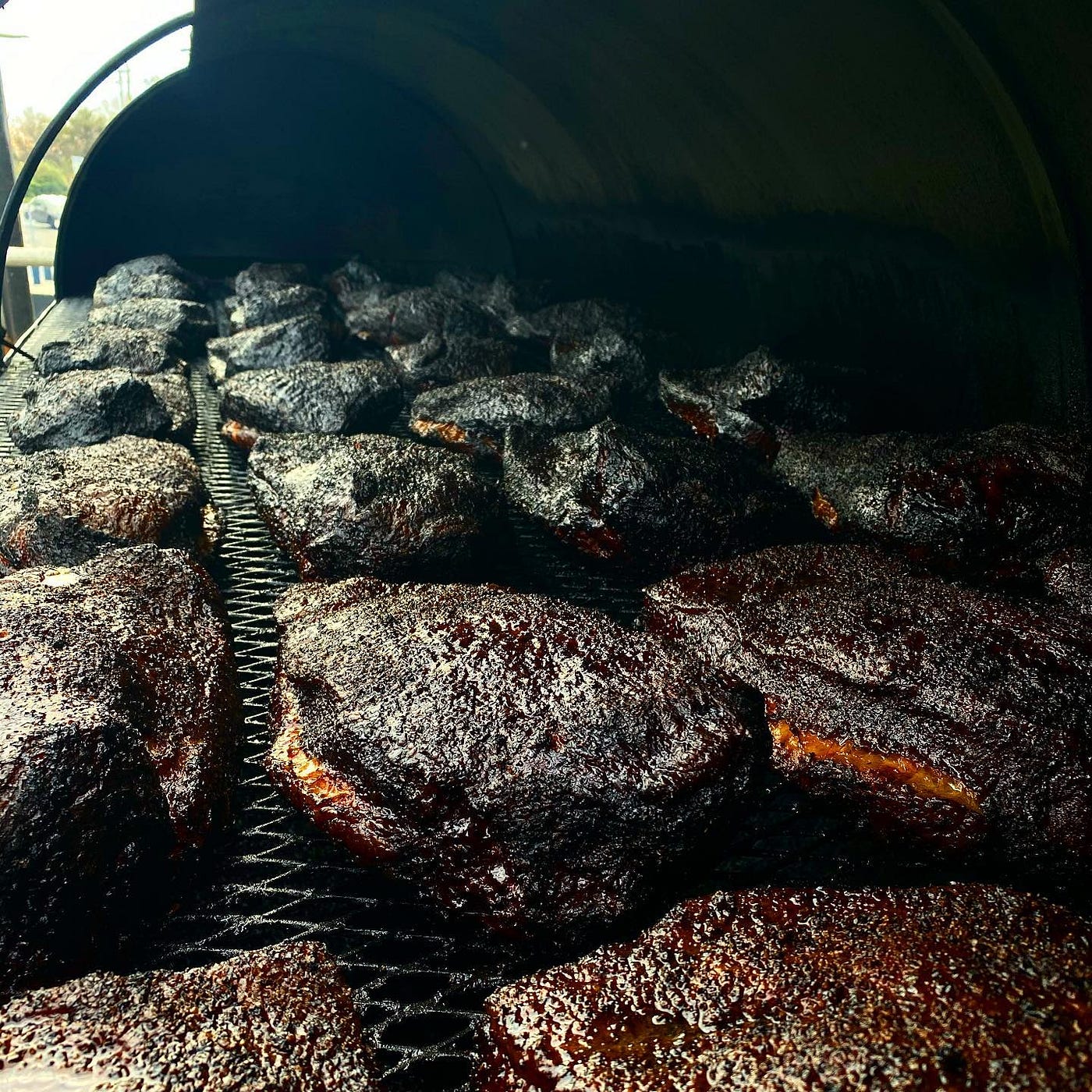 Rows and rows of barbecued pieces of meat in an industrial grill.