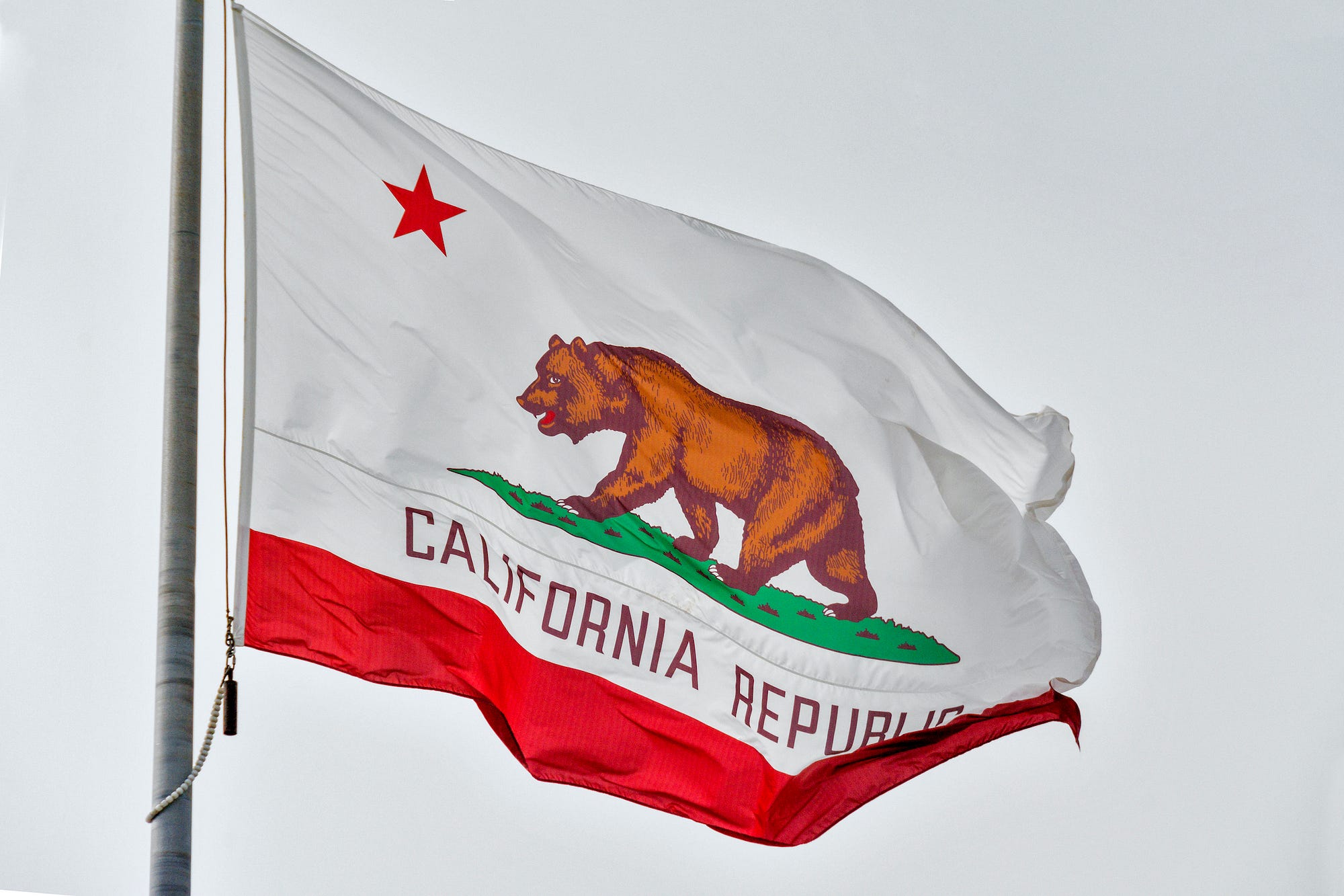California’s state flag, a bear and a red 5-pointed star over the text “California Republic” and a red stripe at the bottom.