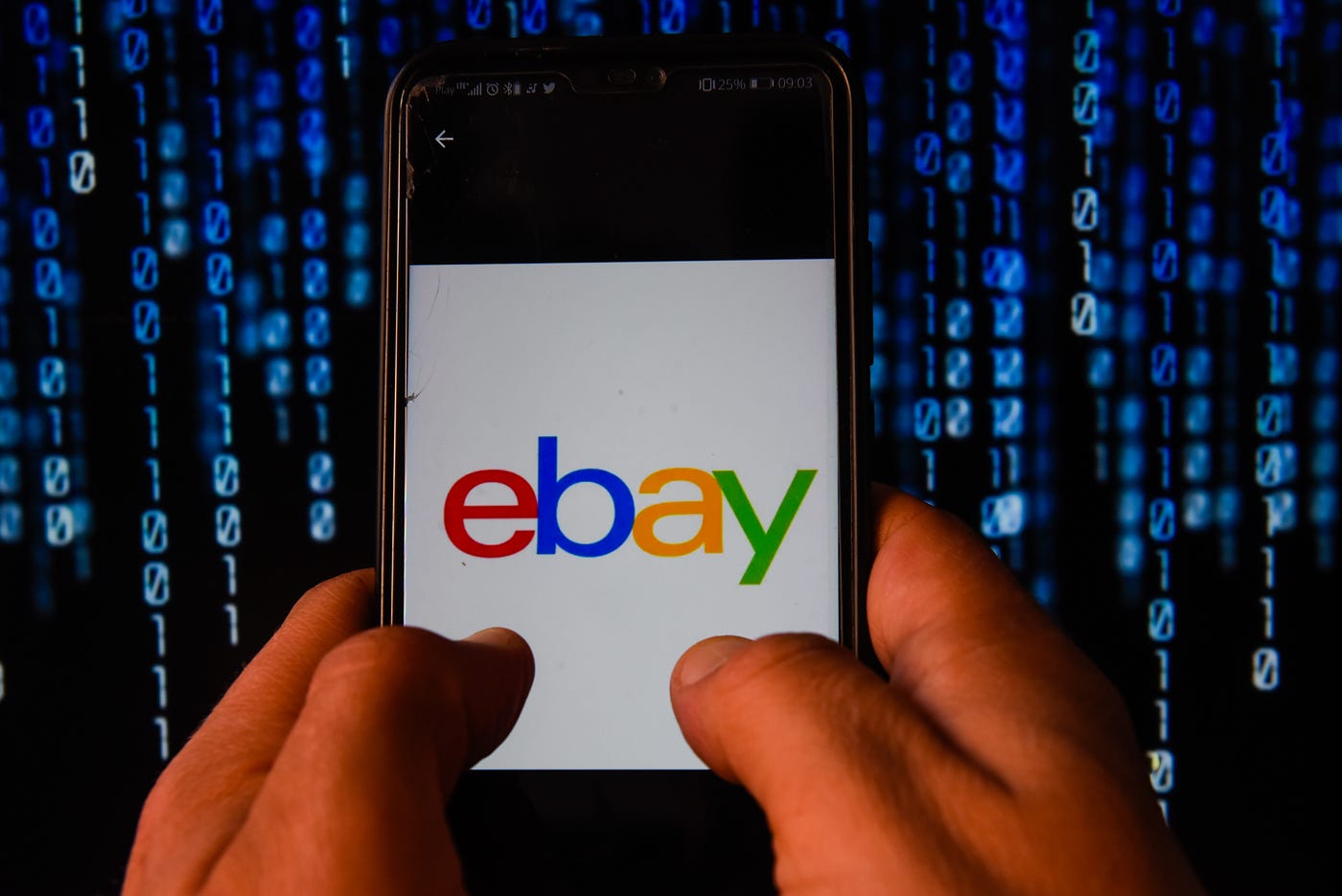Hands holding a phone with the ebay app on its screen. The background is vertical blue characters on solid black.