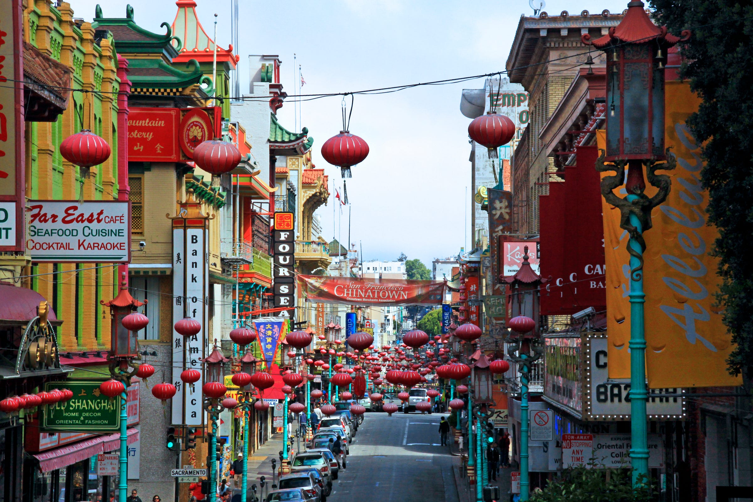 A street with colorful shops and walk-ups, decorated with red paper lanterns.