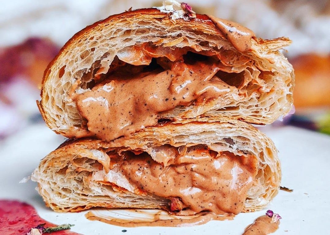 A halved croissant filled with a orangish/pinkish sauce.