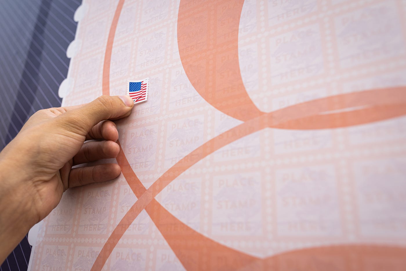 A hand holding a US flag stamp.