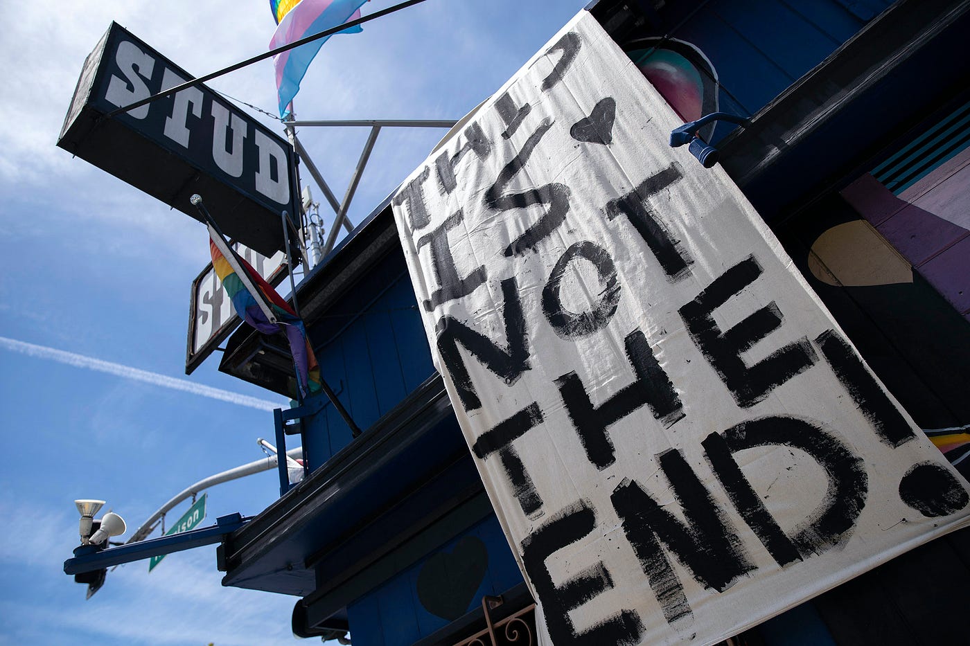 The exterior of the Stud bar. A banner that reads, “This is not the end!” hangs from its roof, a rainbow flag above it.