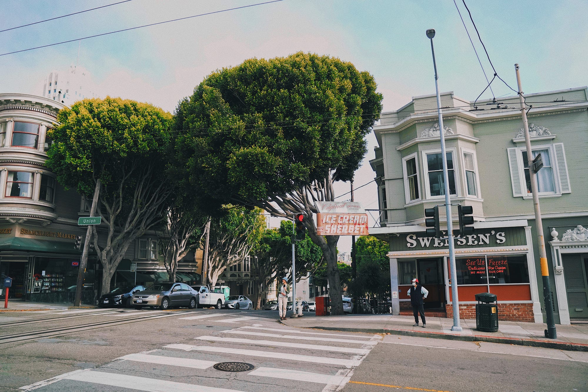 Photo of Swensen’s, taken from across the street. Cars are stopped at the intersection.