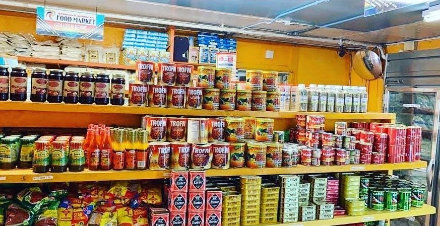 Fully-stocked shelves in a store with goldenrod-colored walls.